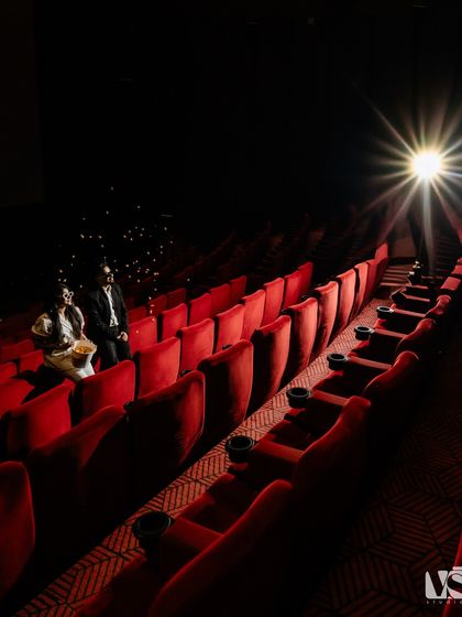 A magical shot in a movie theatre, with popcorn flying in the air like confetti. The single spotlight creates a dramatic, cinematic effect, making their love story the main feature.
