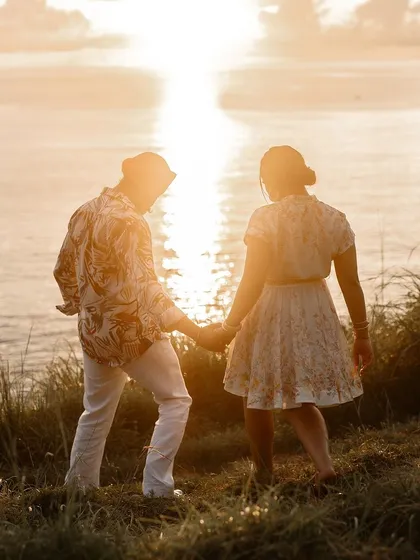 A romantic shot of the couple walking into the sunset on the beach.