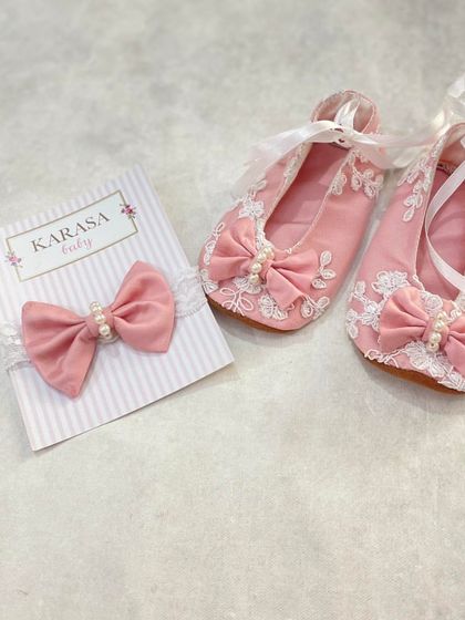 Little booties for little feet. These custom-made pink velvet booties feature delicate lace and pearl details, and come with a matching headband.