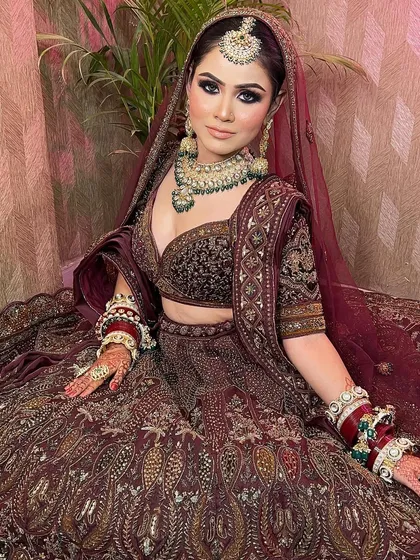 A close-up of a bride in a stunning maroon lehenga, showcasing the intricate embroidery and beautiful makeup.