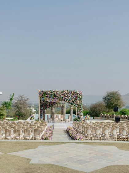 A serene, wide shot of the wedding mandap set against the vast, open landscape. The design feels both grand in its execution and intimate in its placement.