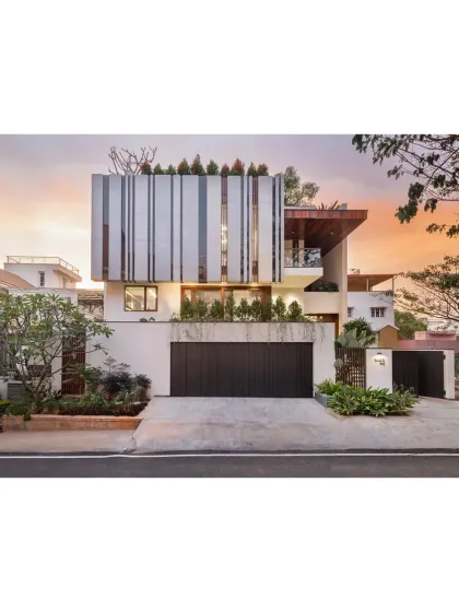 The facade of the House Above The Tree captured at sunset, showcasing how the structure interacts with light. We used clean lines, a rooftop garden, and distinctive vertical louvers to create a modern home that is both private and open to its surroundings. This view highlights the home's strong geometric form against the soft evening sky.