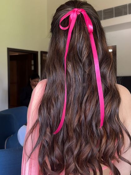A back view of the pink ribbon half-updo, showing how the ribbon adds a pop of color and a touch of playful charm to the classic wavy hairstyle.