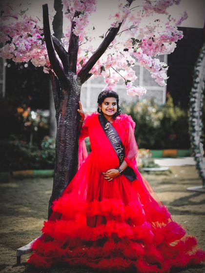 A vibrant and joyful outdoor maternity shoot. The client is wearing my red tiered ball gown, complete with a "Mom to be" sash, creating a celebratory feel.