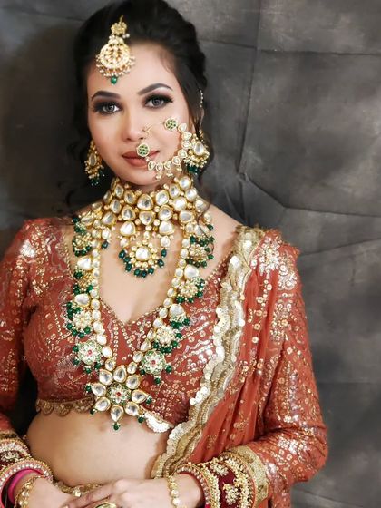 A bride wearing a layered Kundan set with green accents. The long rani haar adds an extra touch of royalty to the ensemble.