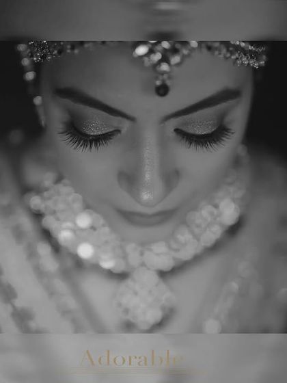 An intimate close-up bridal portrait in black and white. The soft focus on the bride's face highlights her serene expression and intricate floral jewelry, creating a delicate and adorable shot.