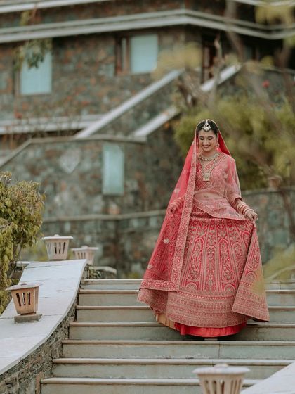 The bride descending the stone steps of the Udaipur venue, a classic and regal bridal portrait.