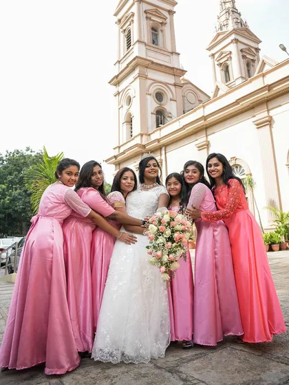 A fun and loving moment between the bride and her bridesmaids, all dressed in matching pink gowns, outside the church.