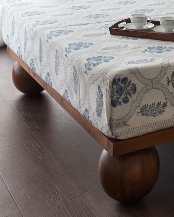 A close-up of a custom-made bed in the West Coast Residence. The spherical wooden legs are a playful and unexpected detail that elevates a simple piece of furniture.