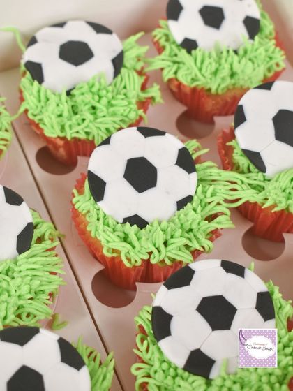These football-themed cupcakes feature buttercream "grass" and fondant soccer balls. They are a perfect addition to a sports party dessert table, offering a simple yet effective themed treat.