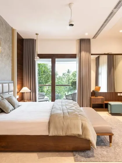 Natural light and views are key in this bedroom. The large windows connect the room to the lush greenery outside, while the mix of wood paneling and concrete-finish walls adds texture and warmth.