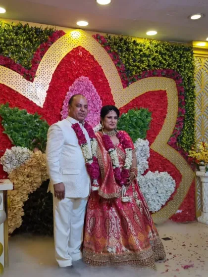 A happy client couple celebrating their special day. She is wearing a beautiful red and gold lehenga, perfectly complemented by his elegant ivory sherwani.