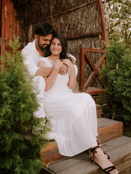 A moment of pure, uninhibited laughter on a rustic wooden porch. Dressed in coordinated white, this couple's joy is infectious, showcasing a perfectly candid moment from their pre-wedding shoot.
