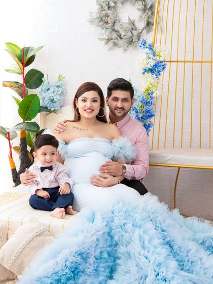 A family portrait filled with love and excitement. The mother's flowing blue gown is the centerpiece of this shot, perfectly complementing the family's coordinated attire.