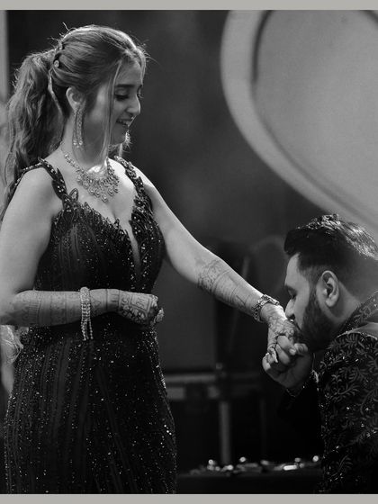 A classic black and white photo of the groom kissing the bride's hand. This timeless, chivalrous gesture is captured beautifully, highlighting the romance of the moment.