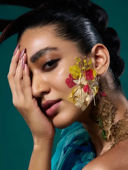 A close-up from the 'Roots' series, showing the delicate detail of the pressed flowers applied to the model's skin.
