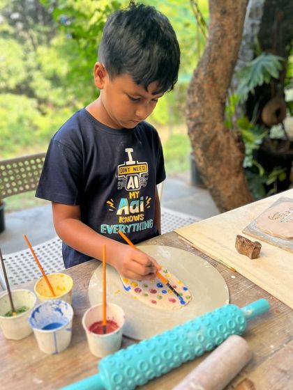 A young artist completely absorbed in painting his creation at my weekend pottery retreat. I provide all the materials and guidance for kids to let their imagination run wild.