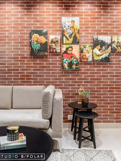 A family photo wall against an exposed brick backdrop adds a deeply personal and warm touch to this living room, turning memories into art.