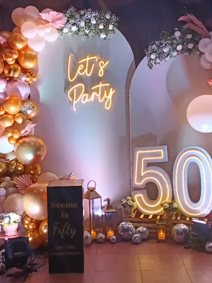 I love bringing grand celebrations to life. This 50th birthday party setup features a stunning balloon arch, a custom 'Let's Party' neon sign, large marquee numbers, and even personalized light-up photo cubes to display cherished memories.
