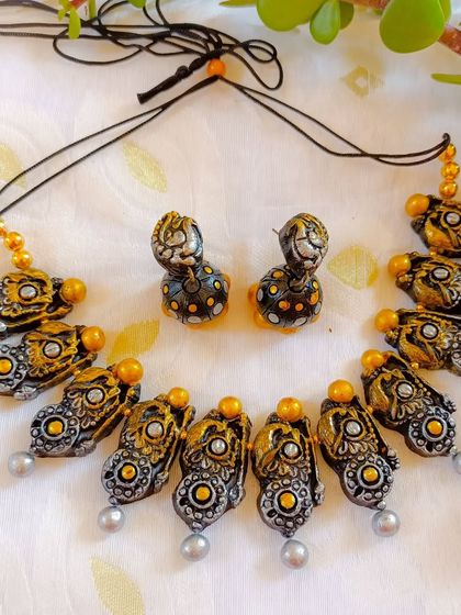 This temple-style necklace features an antique finish with silver and gold tones. The intricate design and pearl-like drops make it a sophisticated choice for ethnic wear.