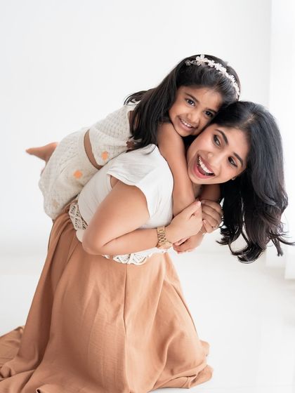 A mother giving her daughter a happy piggyback ride in the studio.