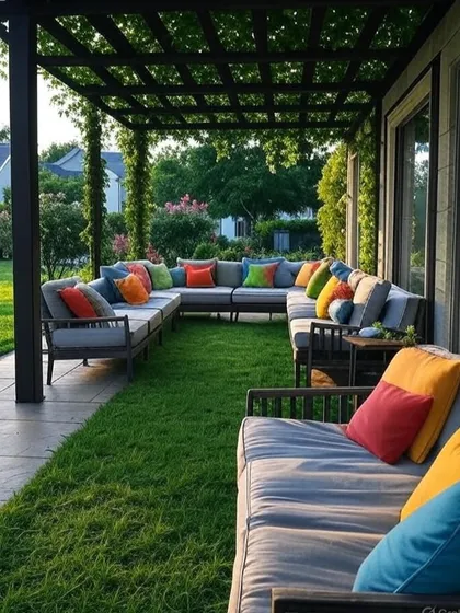 A long, U-shaped outdoor sofa sits perfectly under this dark metal pergola. The design cleverly uses the lawn as a soft, natural carpet for the central area of the lounge.