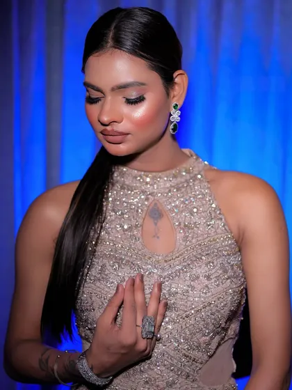 A serene portrait with the model looking down, highlighting the sleek ponytail and modern jewelry.