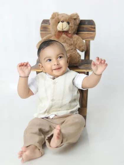 A happy little gentleman in his vest and trousers, enjoying his milestone photoshoot.