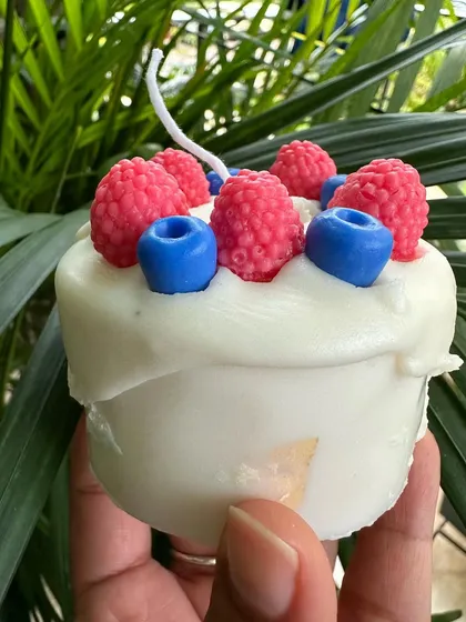 A handcrafted birthday cake candle made entirely of soy wax, complete with berry embeds.