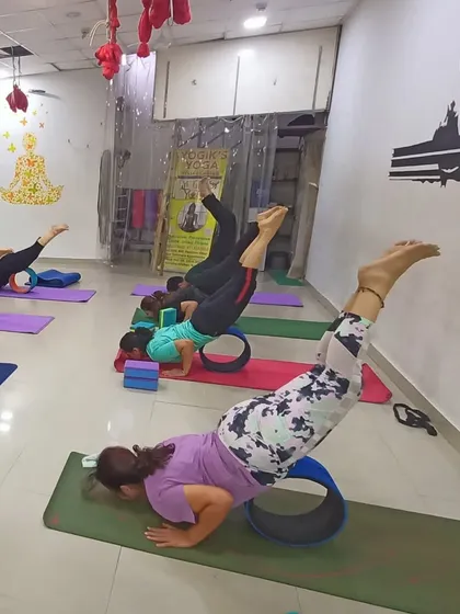 This image shows a creative and challenging way we use the yoga wheel to build core and upper body strength. This variation of a push-up with leg lift requires balance, control, and focus.