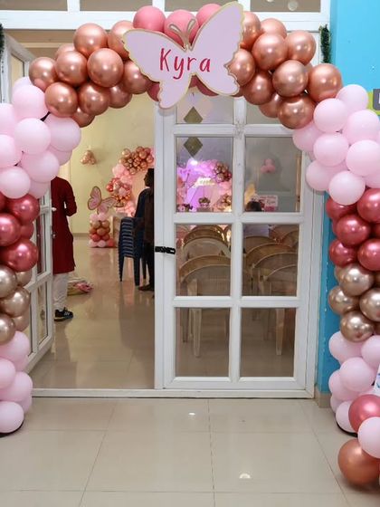 A beautiful entrance for a butterfly-themed party, featuring a balloon arch in rose gold and pink with a custom butterfly name sign.