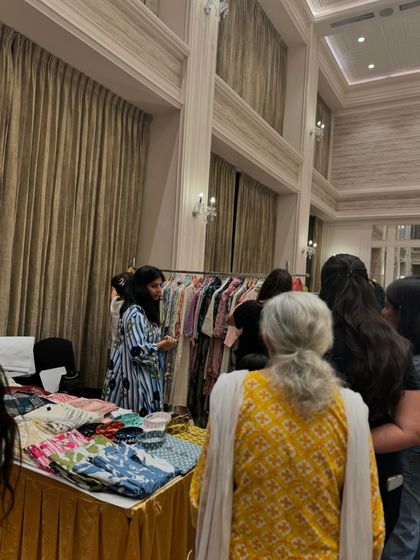 A packed clothing stall with customers eager to see the latest designs. High interest translates directly into high sales potential.