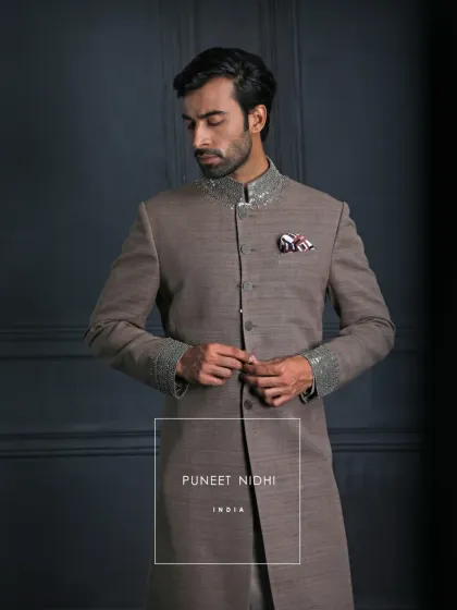 A statement in subtle royalty, this brown matka silk achkan features a jeweled collar and cuffs. It is sophisticated, graceful, and enduring.