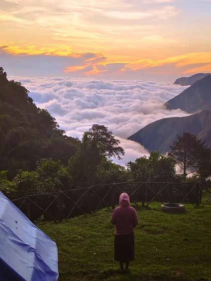 A stunning shot of a person watching the sunrise over the clouds at the Munnar camp.