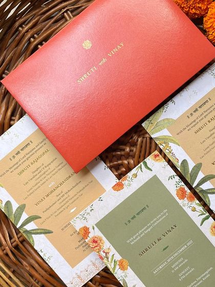 The complete suite for the South Indian wedding, with a vibrant red envelope. The different cards for the Mehendi, Sangeet, and wedding ceremony use a cohesive palette of green, mustard, and orange.