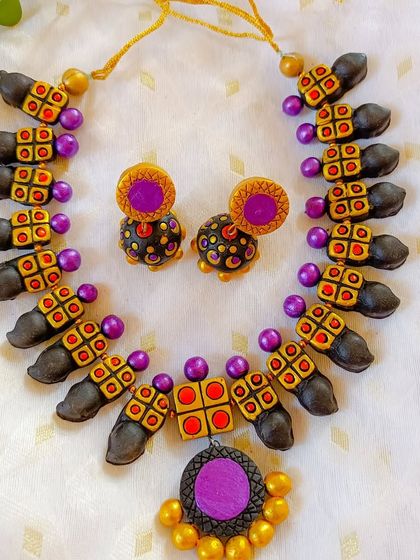 A unique necklace design with square and bud-shaped beads in purple and black.