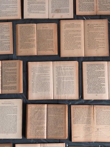 The blank canvas for 'The Villa between Pages': a grid of open vintage books, their aged paper waiting to be transformed into a new story.