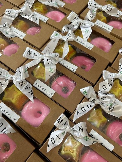 A batch of super cute donut and star-themed return favor boxes, all tied up with my branded ribbon. Each box contains a pink donut soap and a layered star soap.
