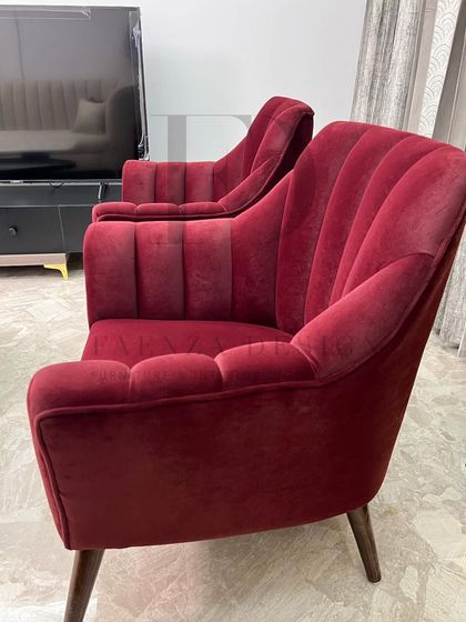 A pair of elegant armchairs in a rich, wine-red velvet. The channel-tufted backs and tapered wooden legs create a look that is both modern and reminiscent of mid-century design.