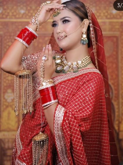 A bride wearing a shimmering red saree-lehenga with golden grid patterns. The matching jewellery and kalire complete this glamorous look.