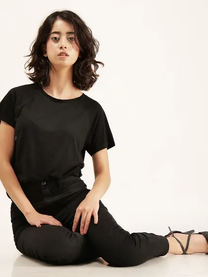 A direct, front-facing seated pose that clearly showcases a basic black t-shirt, a fundamental shot for any clothing catalogue.