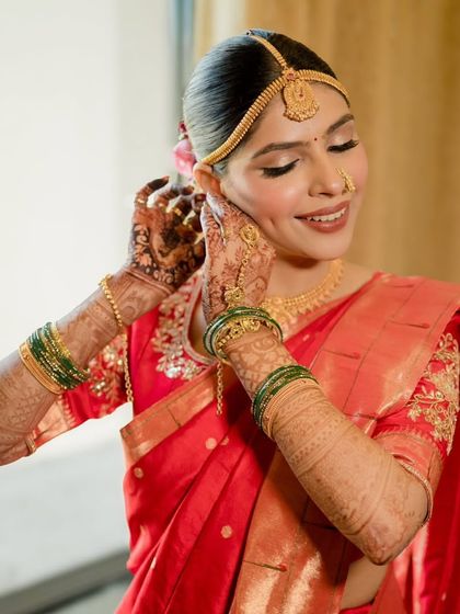 A getting-ready shot that shows the intricate details of the bride's henna and jewelry. The makeup is designed to complement these traditional elements.