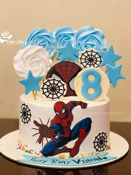 An action-packed Spiderman cake for an 8th birthday. It's decorated with spider webs, stars, and blue and white roses for a cool and stylish superhero theme.