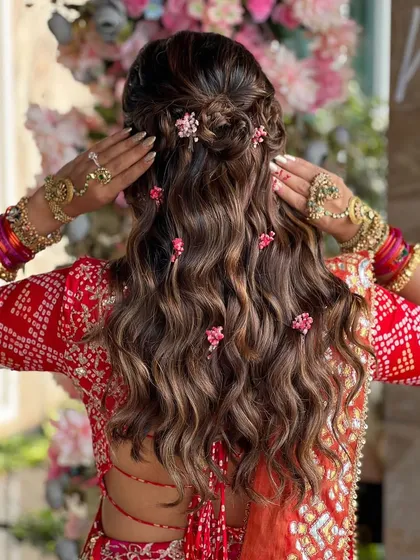 Flowers and curls are a match made in heaven. This half-up braided style is woven with small pink flowers, creating a beautiful, scattered floral effect through the curls.