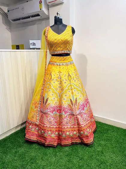 Brighten up any Haldi ceremony with this vibrant yellow lehenga. It features a sequin-embroidered blouse and a multi-colored printed skirt with traditional motifs, offering a festive and cheerful look for daytime wedding events.