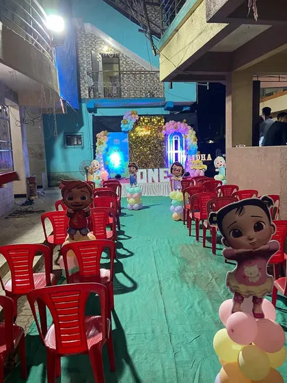 An outdoor Cocomelon themed birthday party setup. The aisle is lined with character cutouts on balloon stands, leading to the main decorated stage.