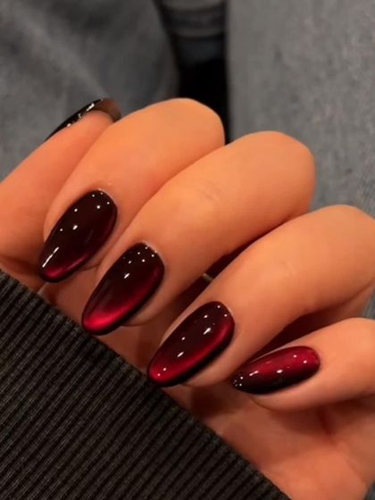 A close-up of these amazing "cat eye" or "velvet" nails in a deep red shade. The effect is mesmerizing.