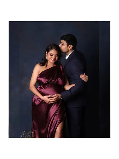 A tender moment between partners. The gentle kiss on the forehead and the protective hand on the bump speak of deep love and excitement.