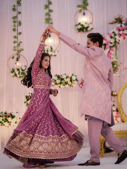 The couple shares a dance at their engagement party, the bride's purple Anarkali twirling beautifully as her partner leads her.