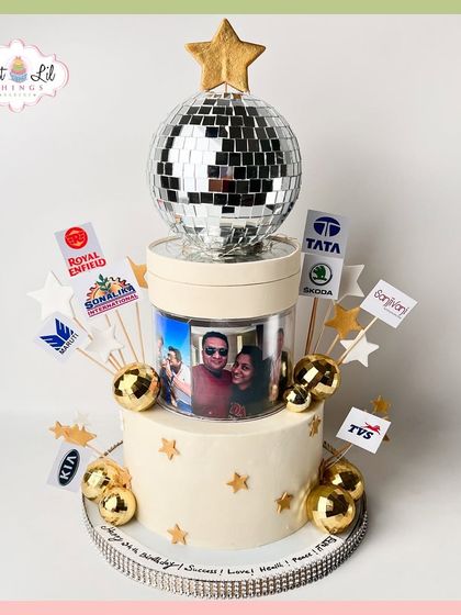 A celebratory cake for a "birthday of success," featuring a disco ball, photos, and logos of various car brands.